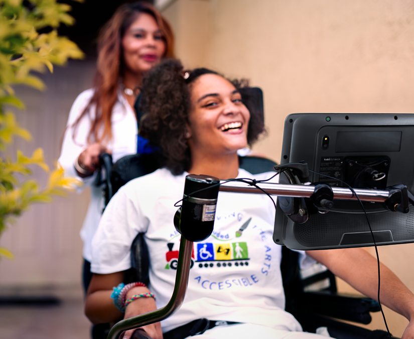 Young woman using her Tobii Dynavox TD I-Series assistive technology device outdoors in a park